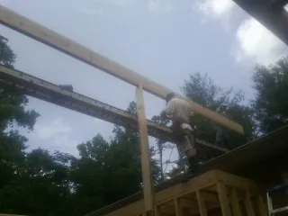 Carpenter setting a ridge beam over a new addition frame — Ice Dam Removal by Roofing Brothers in Clyde